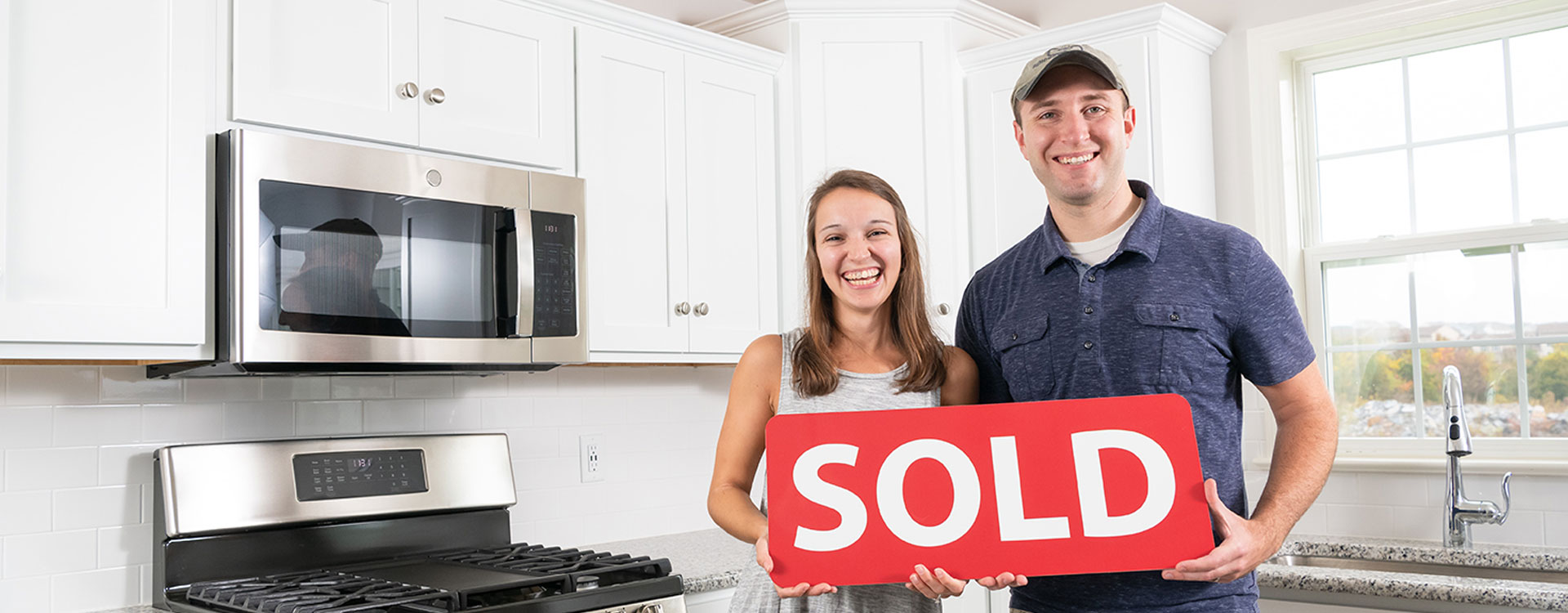 Happy Couple Holding a Sold Sign