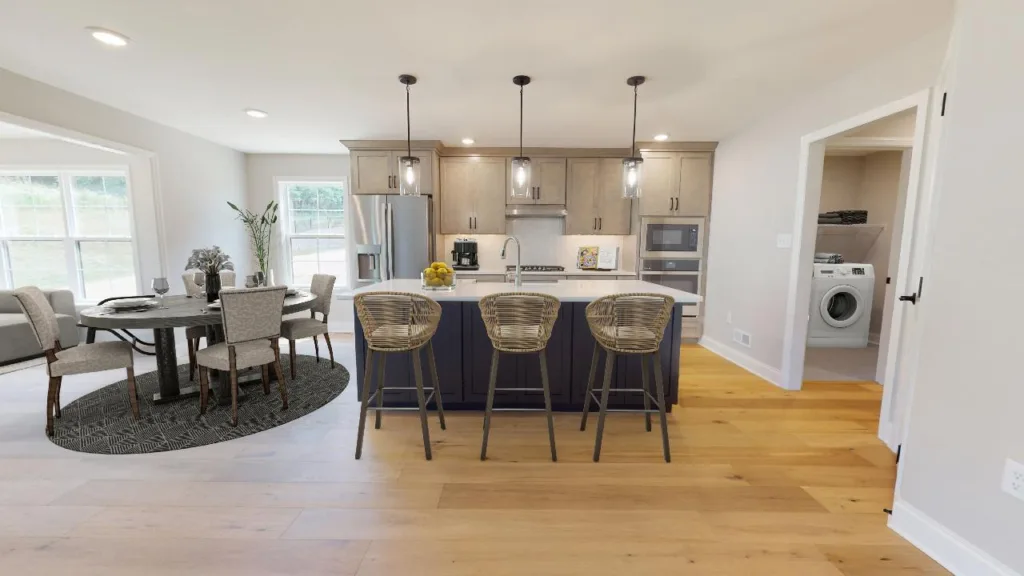 Modern kitchen with a central island and three wicker bar stools, adjacent to a dining area with a round table and four chairs. A laundry room with washer and dryer is visible through an open door.