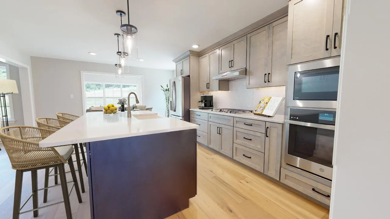 Modern kitchen with light wood cabinets, stainless steel appliances, an island with a white countertop, built-in sink, and three wicker barstools. Large windows provide natural light to the space.