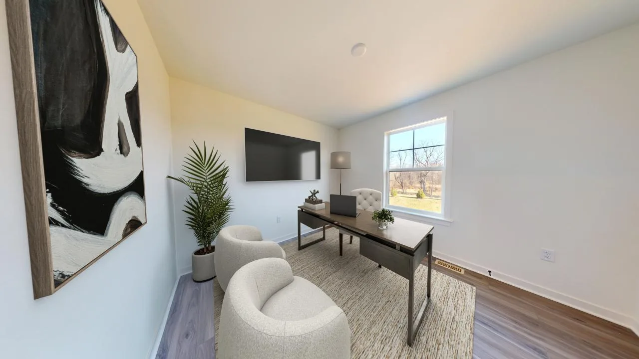 A modern home office with a desk, laptop, lamp, two cream chairs, a potted plant, abstract wall art, a TV, and a large window letting in natural light. The floor is wood, and a beige rug covers part of it.