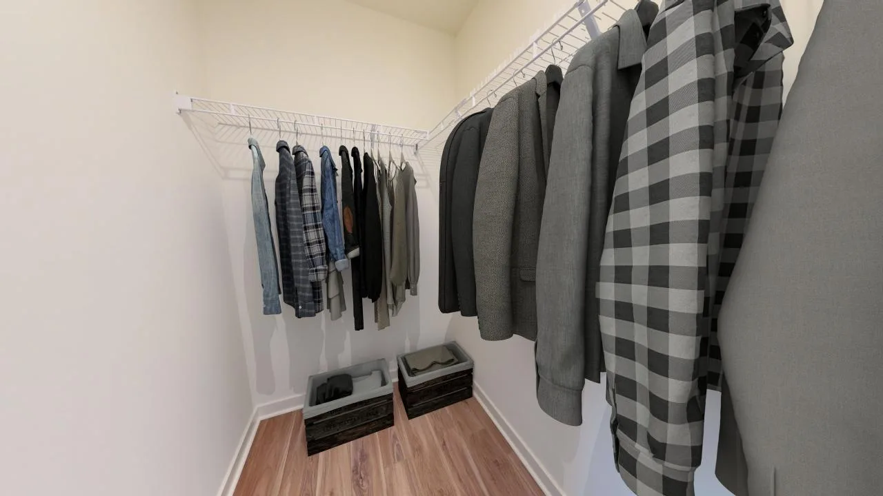 A walk-in closet with wire shelves holding various mens jackets and shirts, mostly in gray tones. Two wooden crates are on the floor, and the closet has light-colored walls and a wood floor.
