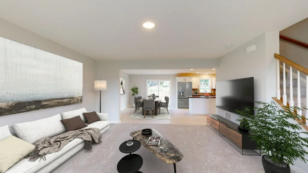 Modern living room with a white sofa, a large wall art, a floor lamp, a coffee table, a flat-screen TV, a plant, and an open view of a dining area and kitchen in the background. Stairs are visible to the right.