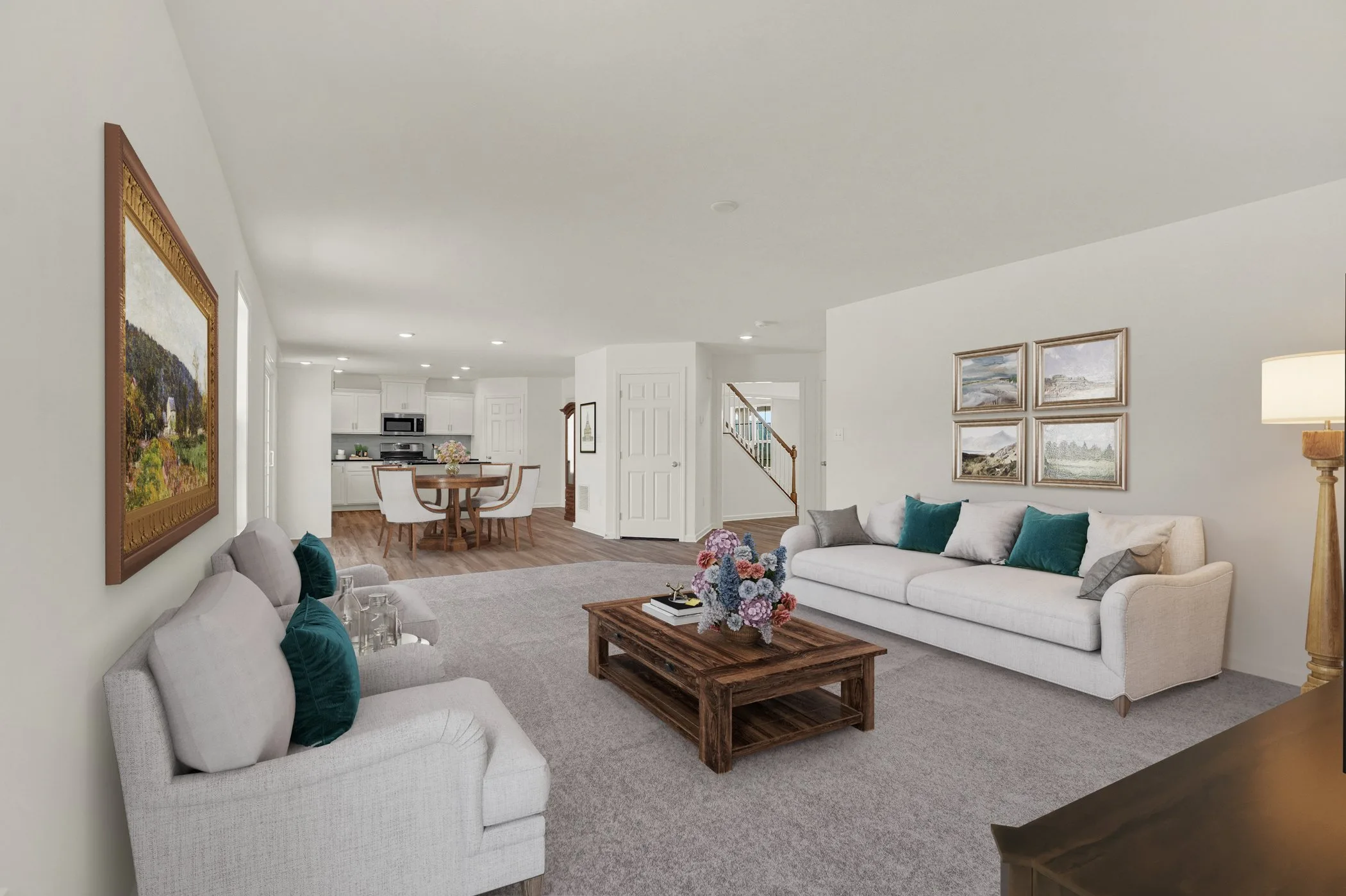 A bright, open-concept living room with two light-colored sofas, teal accent pillows, a wooden coffee table with a flower arrangement, and a view into a dining area and modern kitchen in the background.
