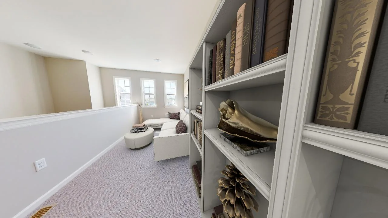 A cozy, carpeted loft area featuring a white bookshelf filled with books and decorative items. In the background, a white couch and round ottoman sit near three bright windows.