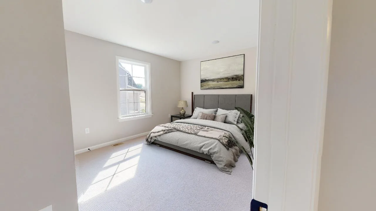 A bright, minimalist bedroom with a large window, a bed with gray headboard and neutral bedding, a bedside table with a lamp, and a large landscape painting above the bed.